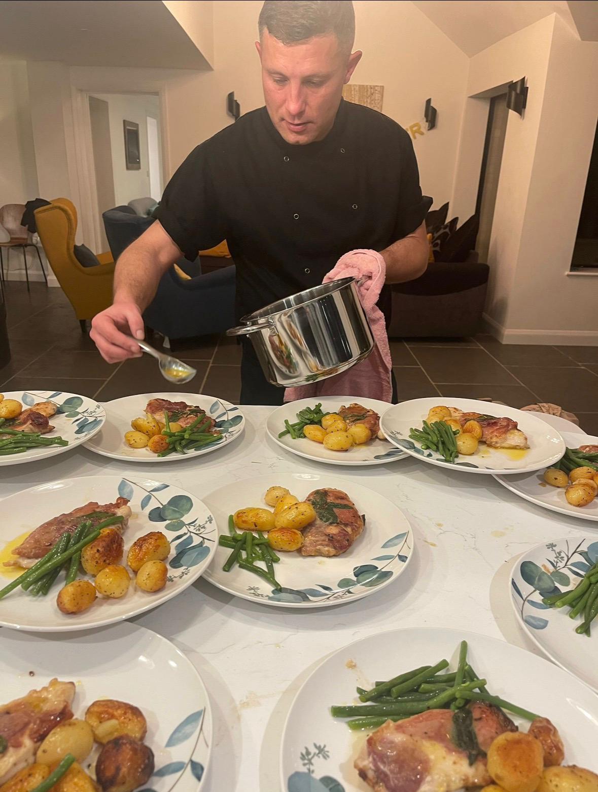Chef plating saltimbocca with crispy potatoes and green beans